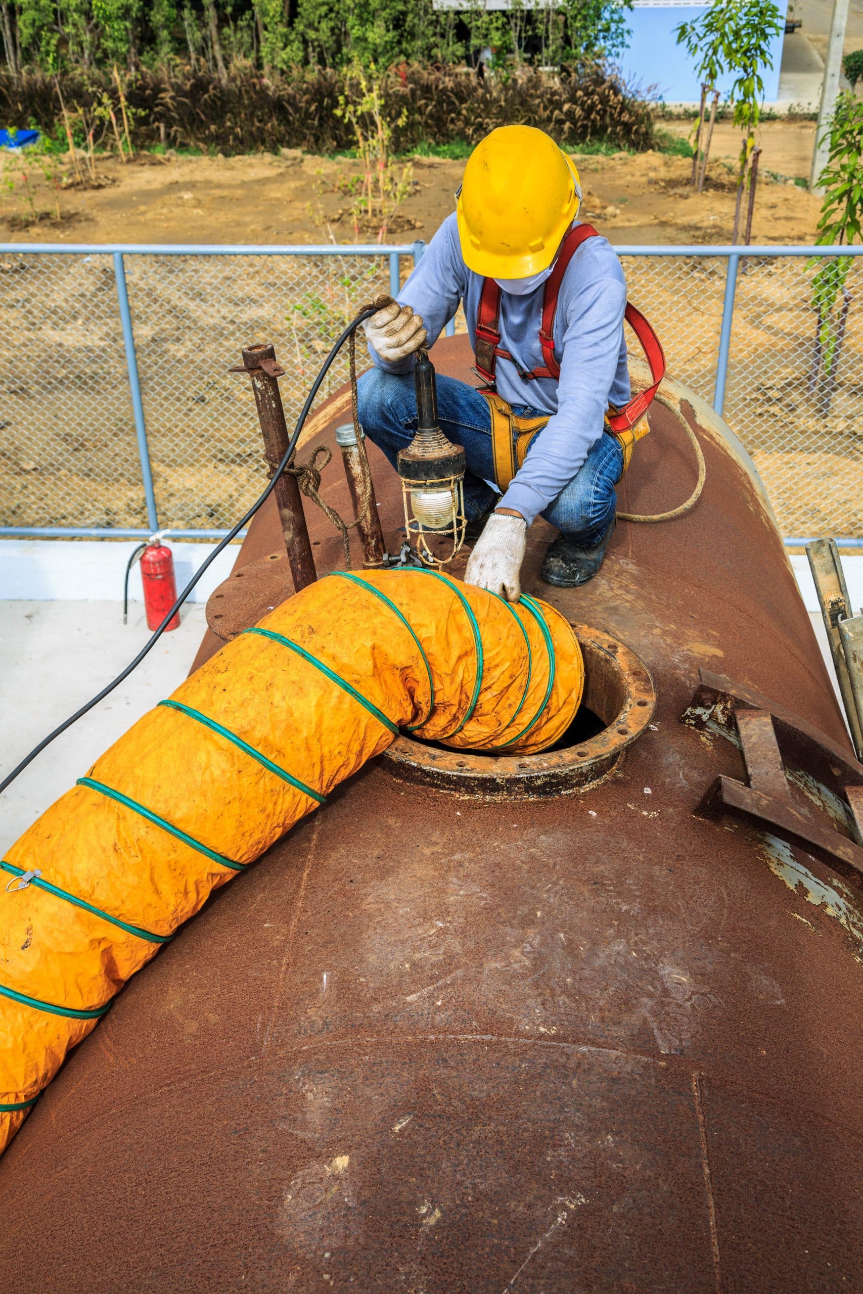 A confined space rescue member holds a light and monitors the exit of a confined space entry point